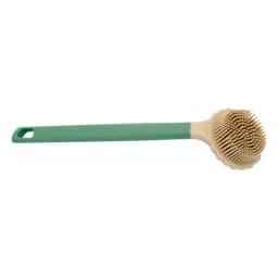 Green and beige silicone back scrubber with a long handle lying on a light countertop with plants in the background. - view 2
