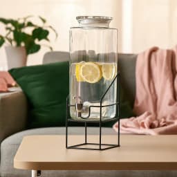 Clear rectangular glass beverage dispenser with a silver spigot and a matching glass lid, sitting on a black wire metal stan… - view 4