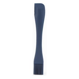 Dark grey silicone basting brush with a long handle lying on a beige kitchen counter next to a small bowl of chopped apples. - view 3