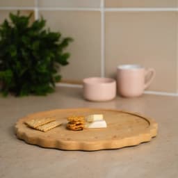 Round light brown bamboo coaster with scalloped edges and small circular indentations, resembling a biscuit, on a white back… - view 1