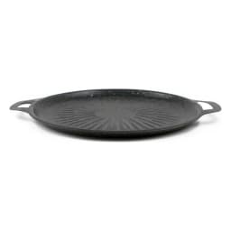 Black round cast iron grill pan with ribbed surface, cooking meat and vegetables on a light kitchen counter. - view 2