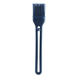 Single dark blue silicone basting brush with a long handle, lying on a light kitchen counter next to small bowls. - view 2