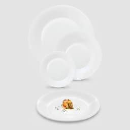 A collection of white round glass dinner plates of various sizes, with one plate in the foreground holding a small salad por… - view 2