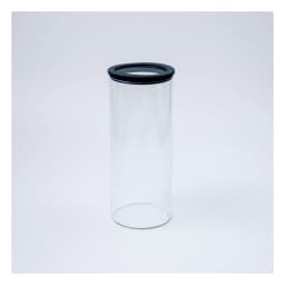 Single clear cylindrical glass storage jar with a black lid on a white background - view 2