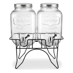 Two clear glass beverage dispensers with silver lids and spigots on a black metal stand against a white background. - view 3
