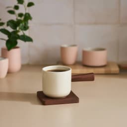 Cream ceramic mug with dark brown wooden handle and matching square wooden coaster on a white background - view 1