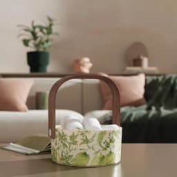 Round glass serving basket with a cream interior and green floral pattern on the exterior, featuring a brown wooden handle. - view 4