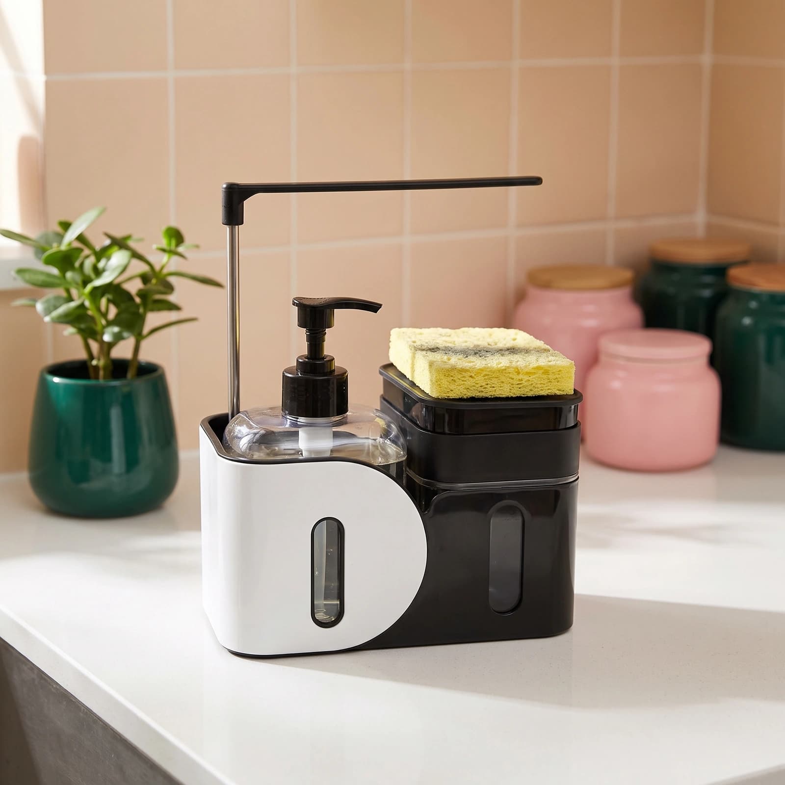 Black and white plastic kitchen sink organizer with a clear soap dispenser, a black sponge holder, and a yellow sponge on a…