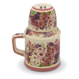 Cream porcelain jug with a handle and a matching cup stacked on top, both adorned with pink and purple floral patterns, on a… - view 2