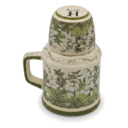 Cream porcelain jug with green floral pattern and matching cup inverted on top, on a kitchen counter. - view 3