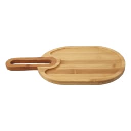Light brown oval wood serving board with a handle and two recessed compartments on a white background. - view 3
